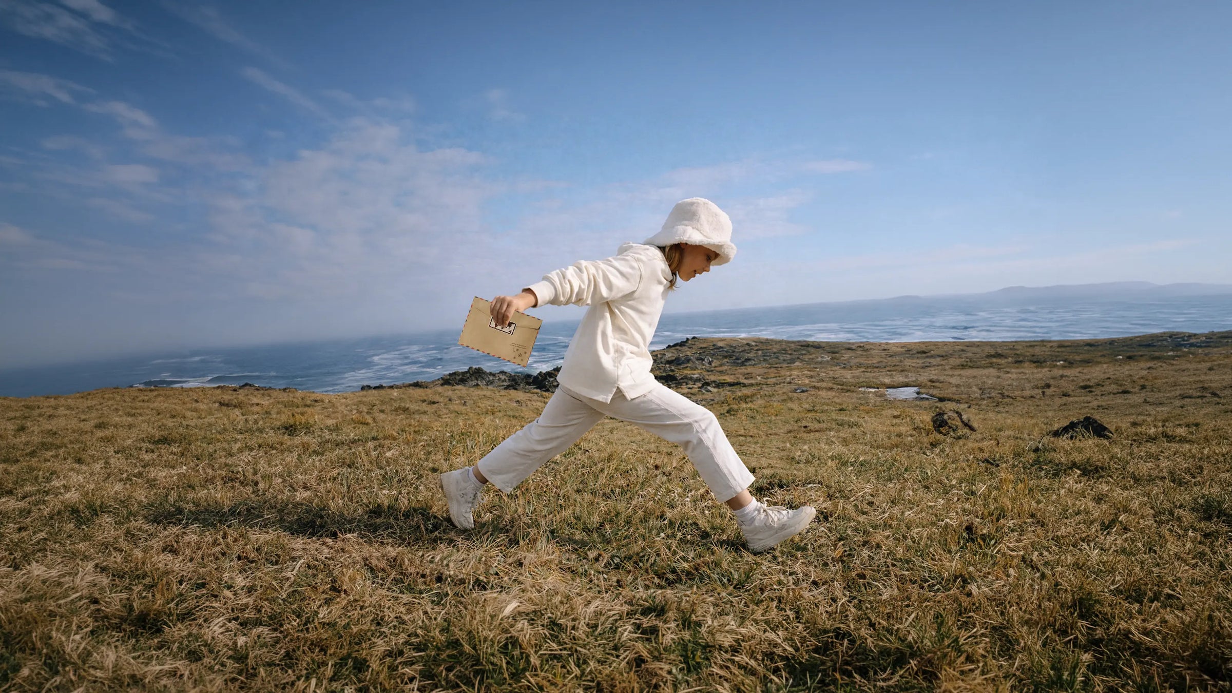 Child walking through a coastal landscape with a letter
